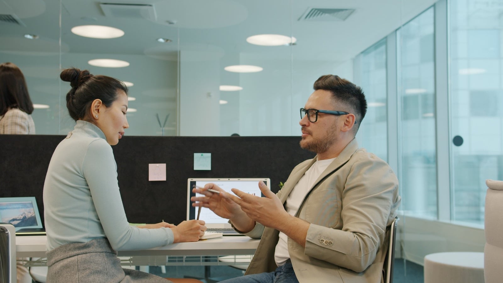 Two professionals having a thoughtful conversation in a sunlit workspace